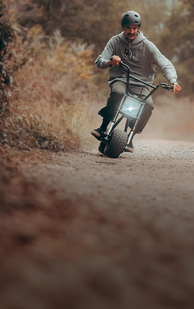Helmeted rider on an Antic electric mini bike on a dirt path
